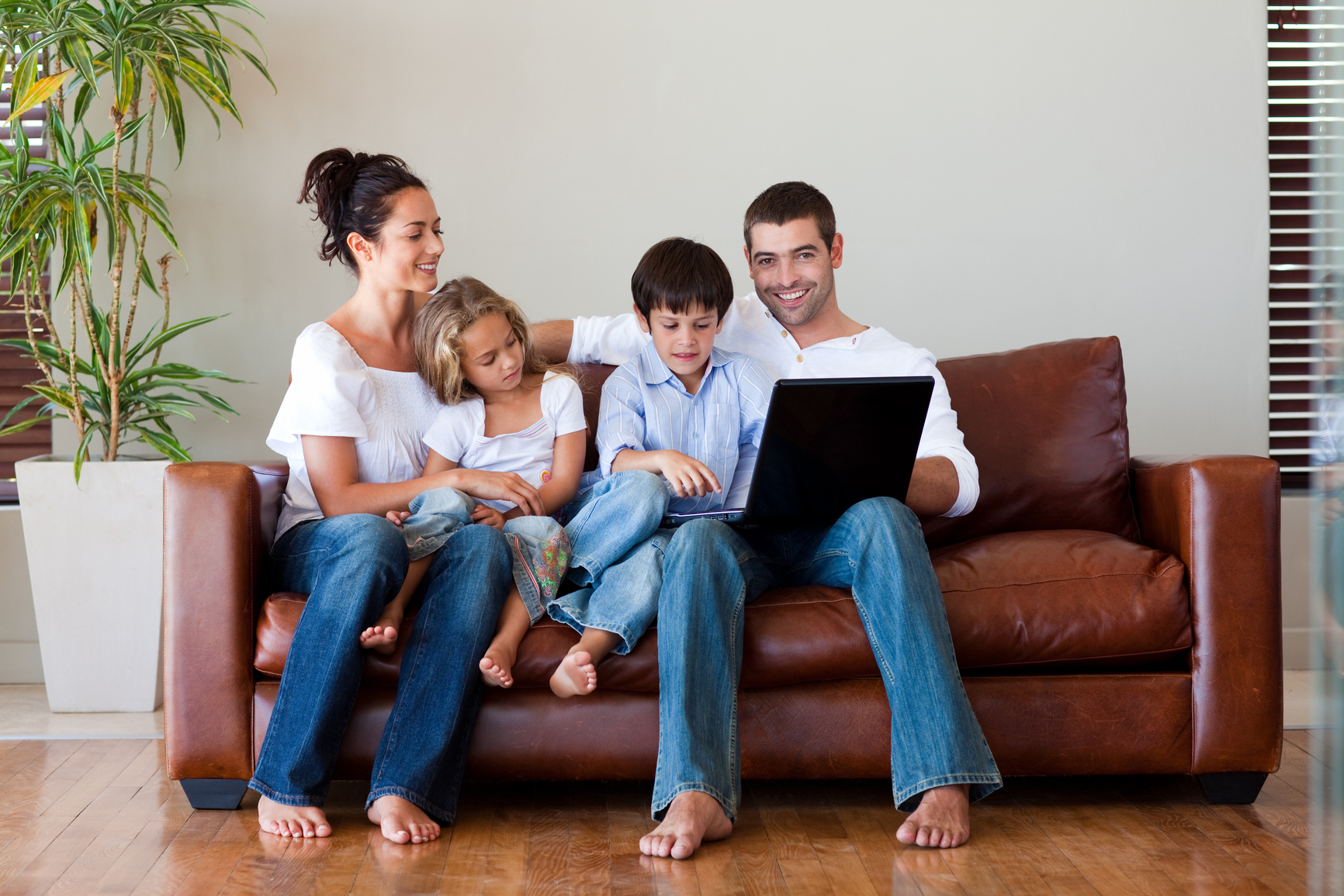 Family playing together with a laptop on a couch